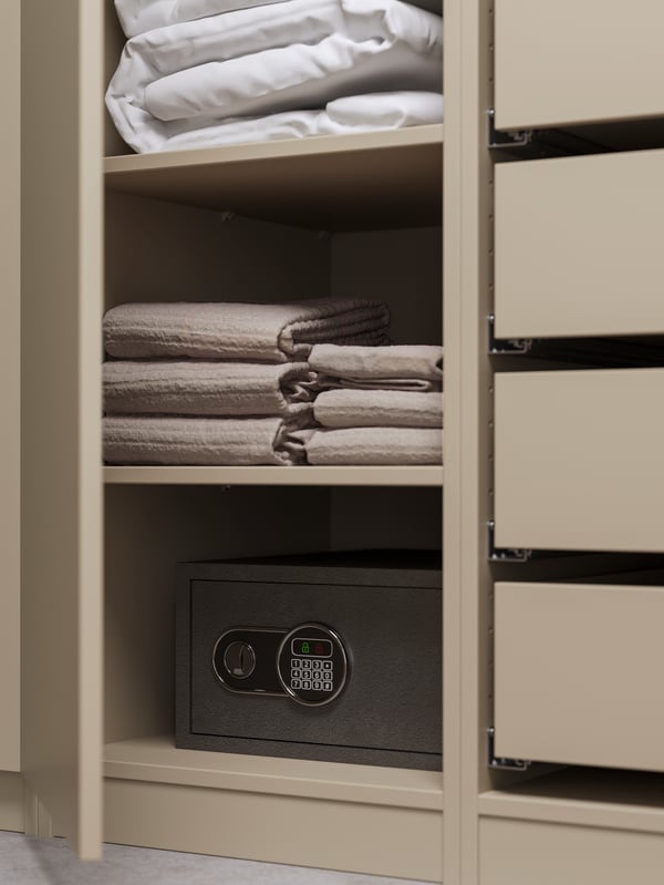 Drawers and shelves with a FJÄLLARNIKA all seasons duvet, VÅGSJÖN bath towels and a safe inside a PAX wardrobe.