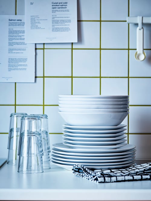 Kitchen counter with tile wall, with an 18-piece VÄRDERA service, LACKTICKA tea towel, and multiple IKEA 365+ glasses.