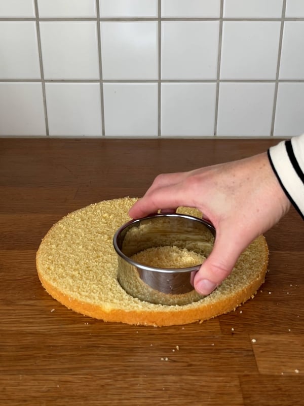 En person använder en LÄTTBAKAD kakskärare för att skära ut en bit tårtbotten.