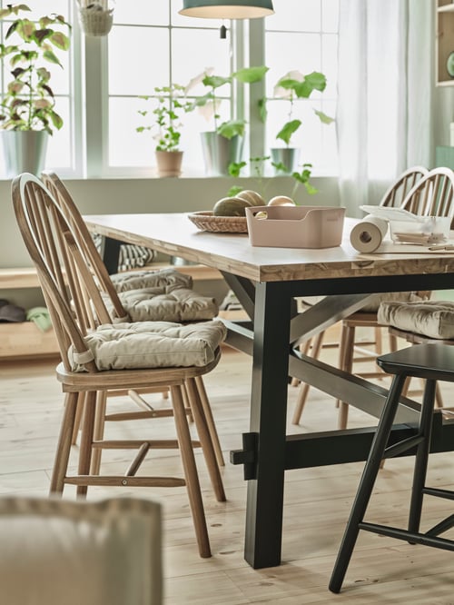 Dining area with a brown SKOGSTA chair with a MALINDA chair cushion, next to a rectangular SKOGSTA dining table with a box.