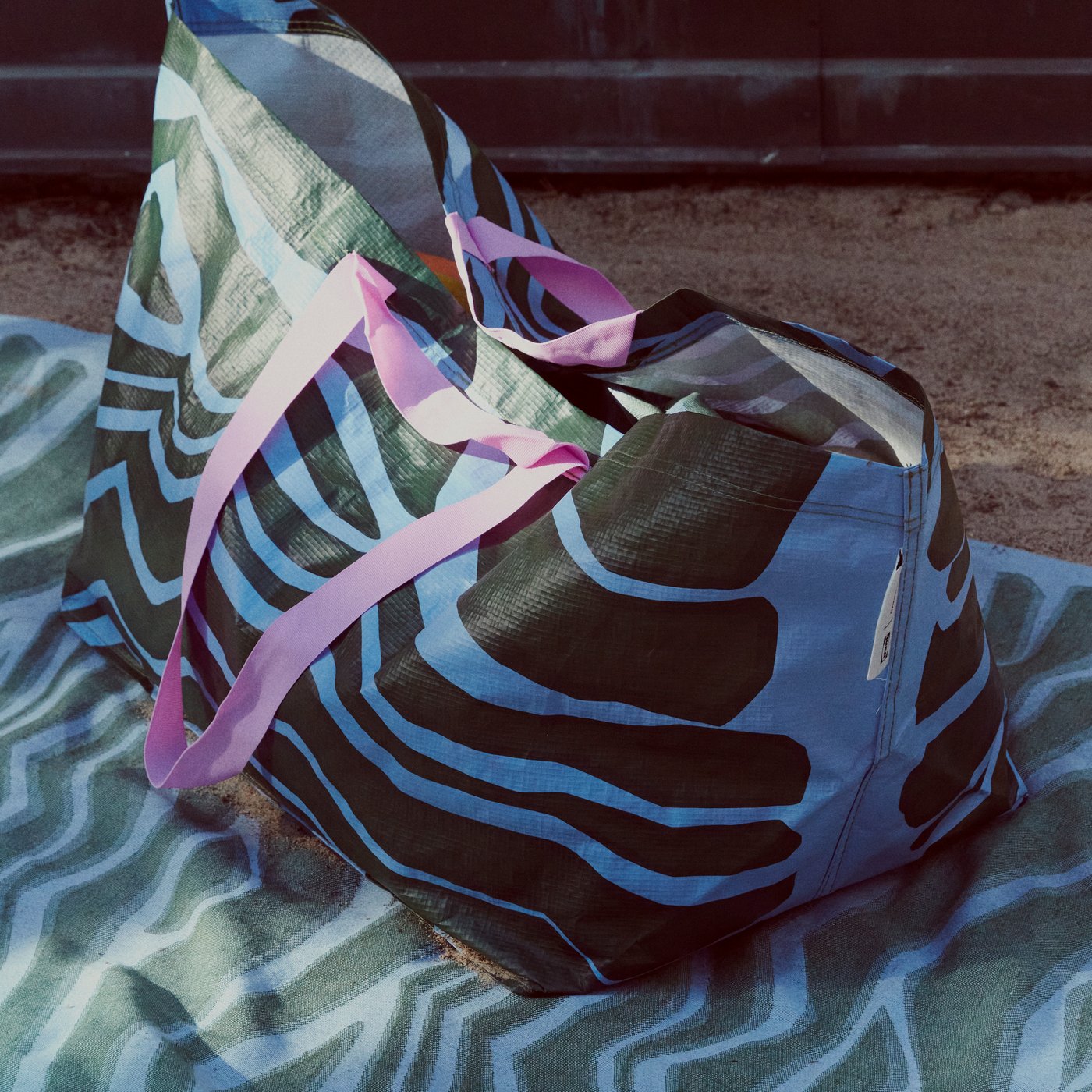 A person is holding a BASTUA carrier bag with a leaf pattern and two large rhubarb leaves to hide their face.