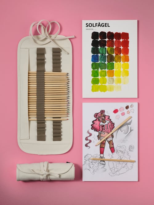 A SOLFÅGEL 3-piece drawing set with a colorful drawing beside it, placed on a pink background.