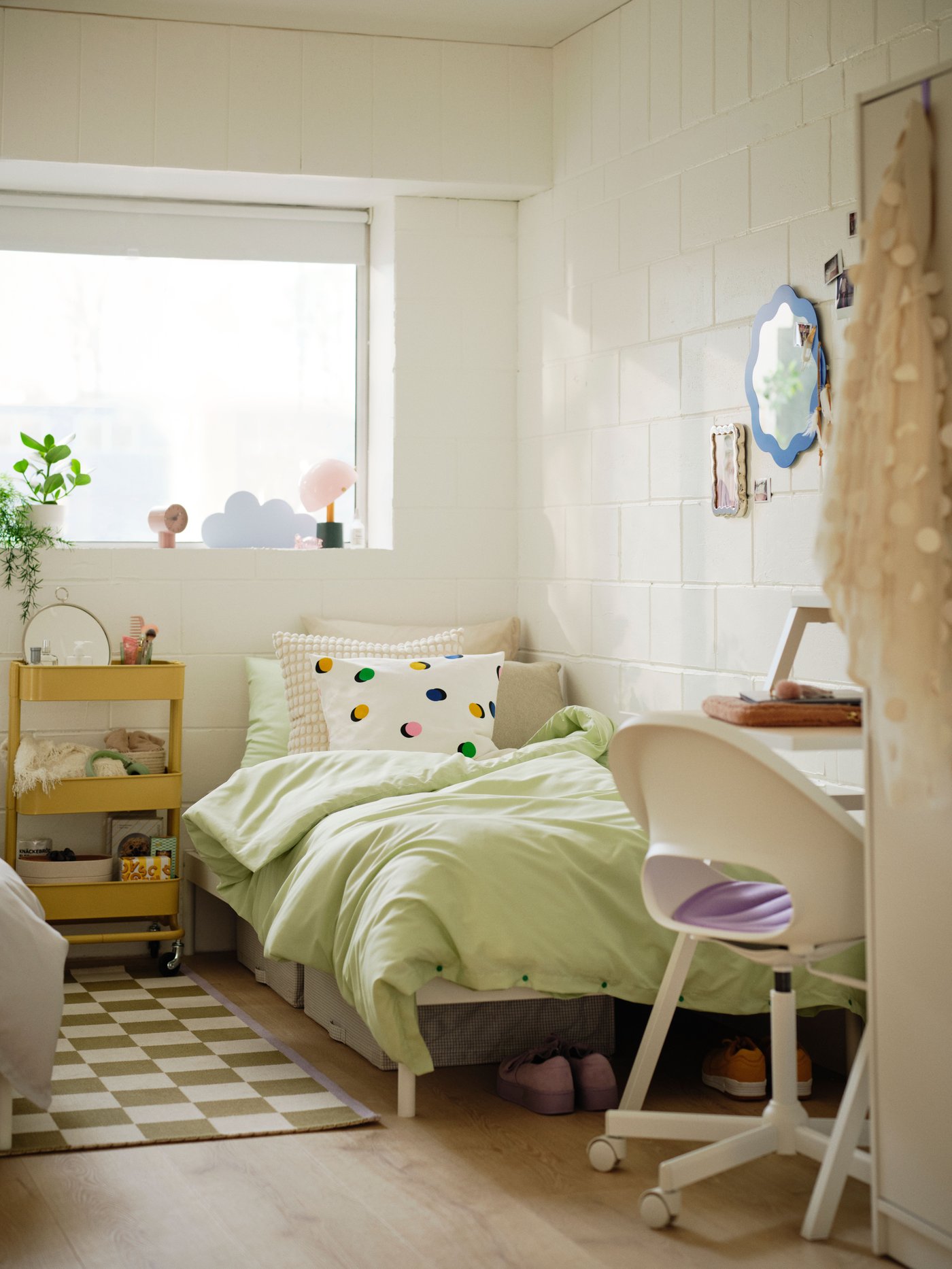 Ett ljust och ungdomligt sovrum med gröna detaljer och en rutig matta.