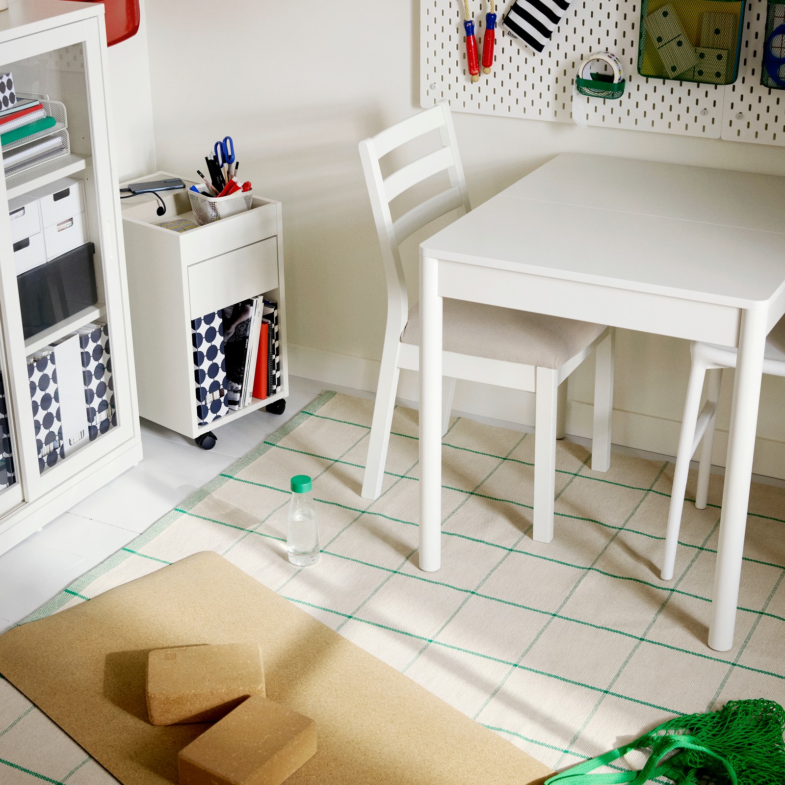 Unha mesa extensible TONSTAD branca nunha estancia con cadeiras TONSTAD brancas e un moble de caixóns con rodas TONSTAD branco.