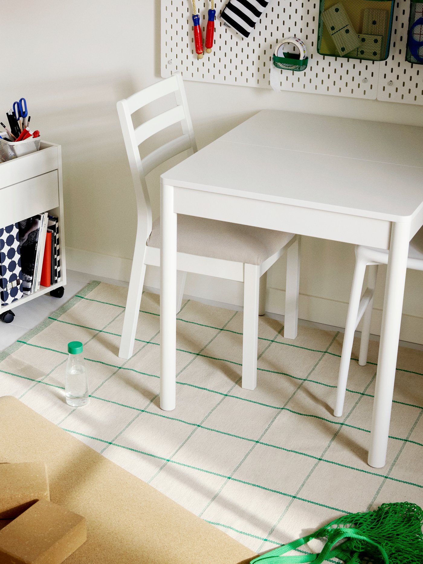 Table à rallonge TONSTAD blanche et chaises TONSTAD blanches, près d’un caisson à tiroirs sur roulettes TONSTAD blanc.