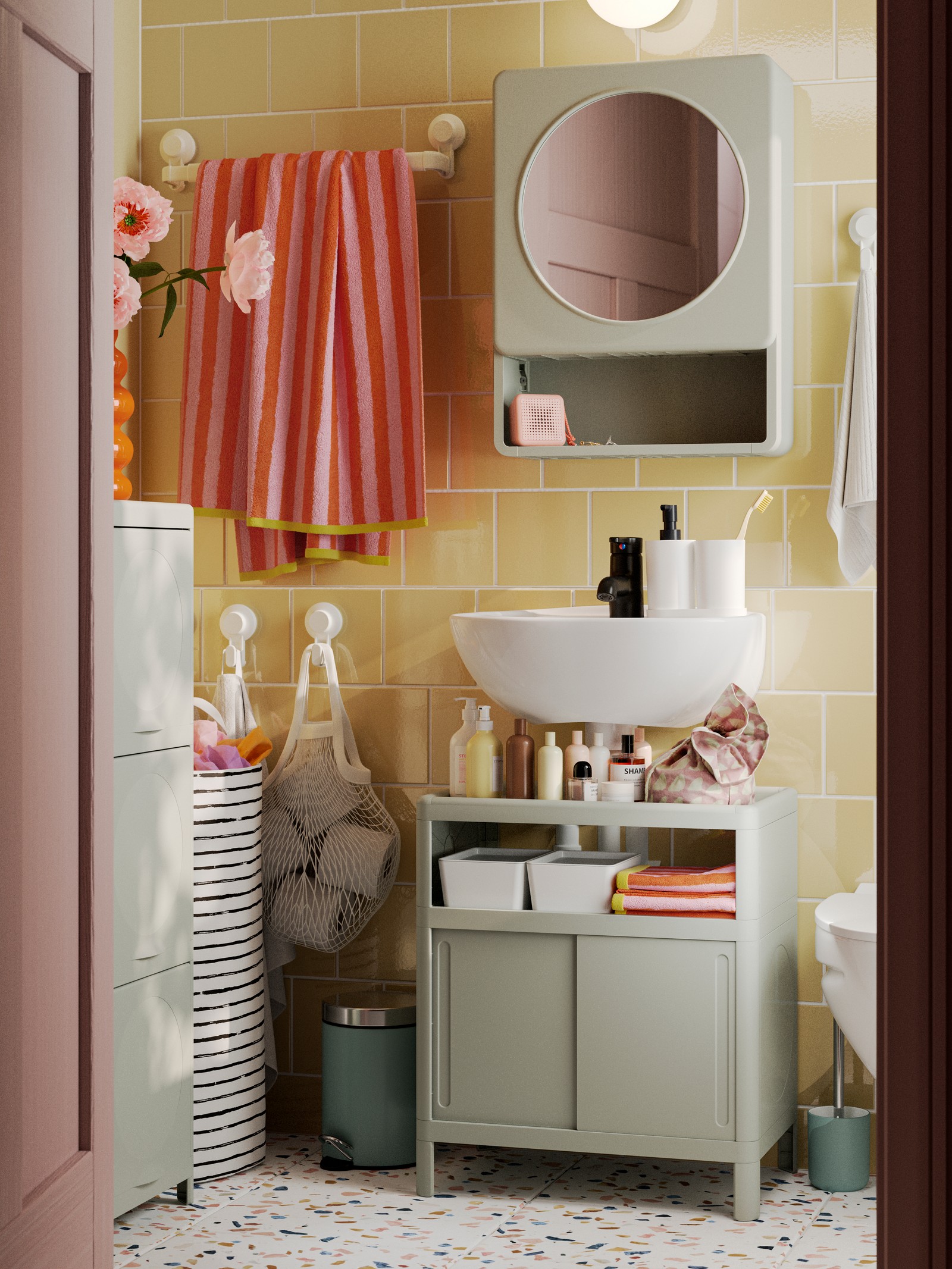 A green IVÖSJÖN wash-basin base cabinet, a cabinet with doors and a mirror cabinet are placed in a yellow-tiled bathroom.