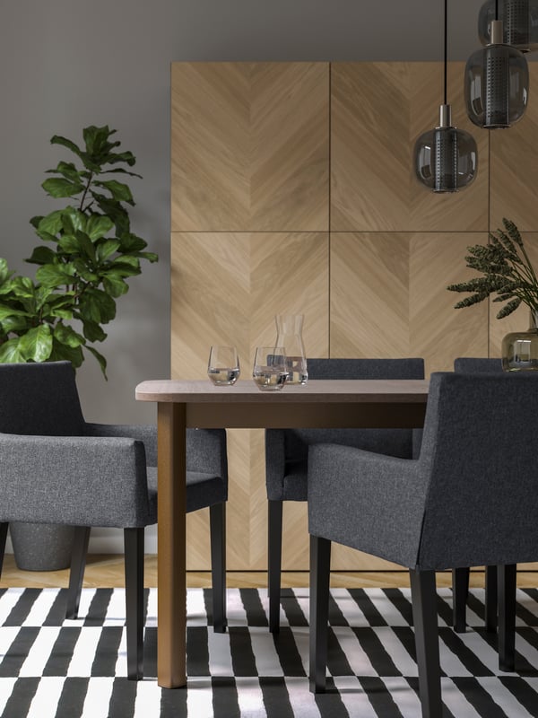 A dining table with dark grey MÅRENÄS dining chairs and a black and white STOCKHOLM rug on the floor.