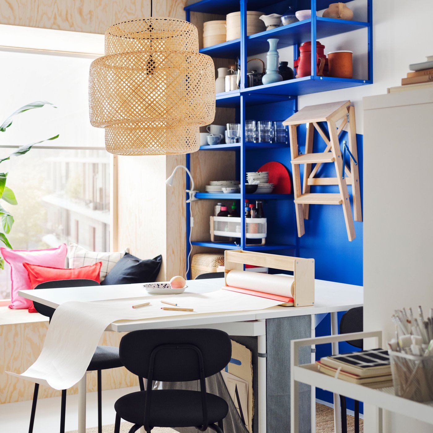 A white and light grey KALLHÄLL gateleg table with storage and two ÖSTANÖ chairs in front of a PLATSA open shelving unit.