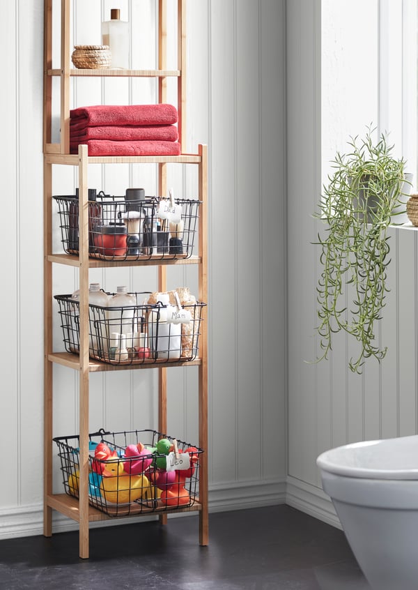 A black PLEJA wire basket with handle in the bathroom