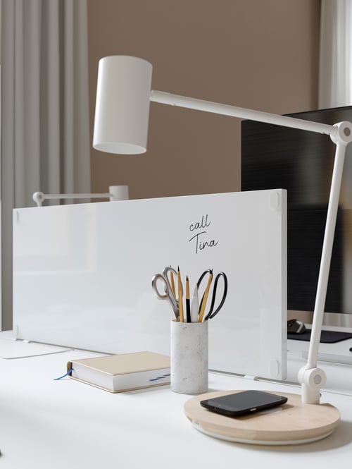Un spațiu de lucru modern, care dispune de un birou cu un panou de informare gri lângă o lampă de lucru cu LED-URI cu încărcare wireless.