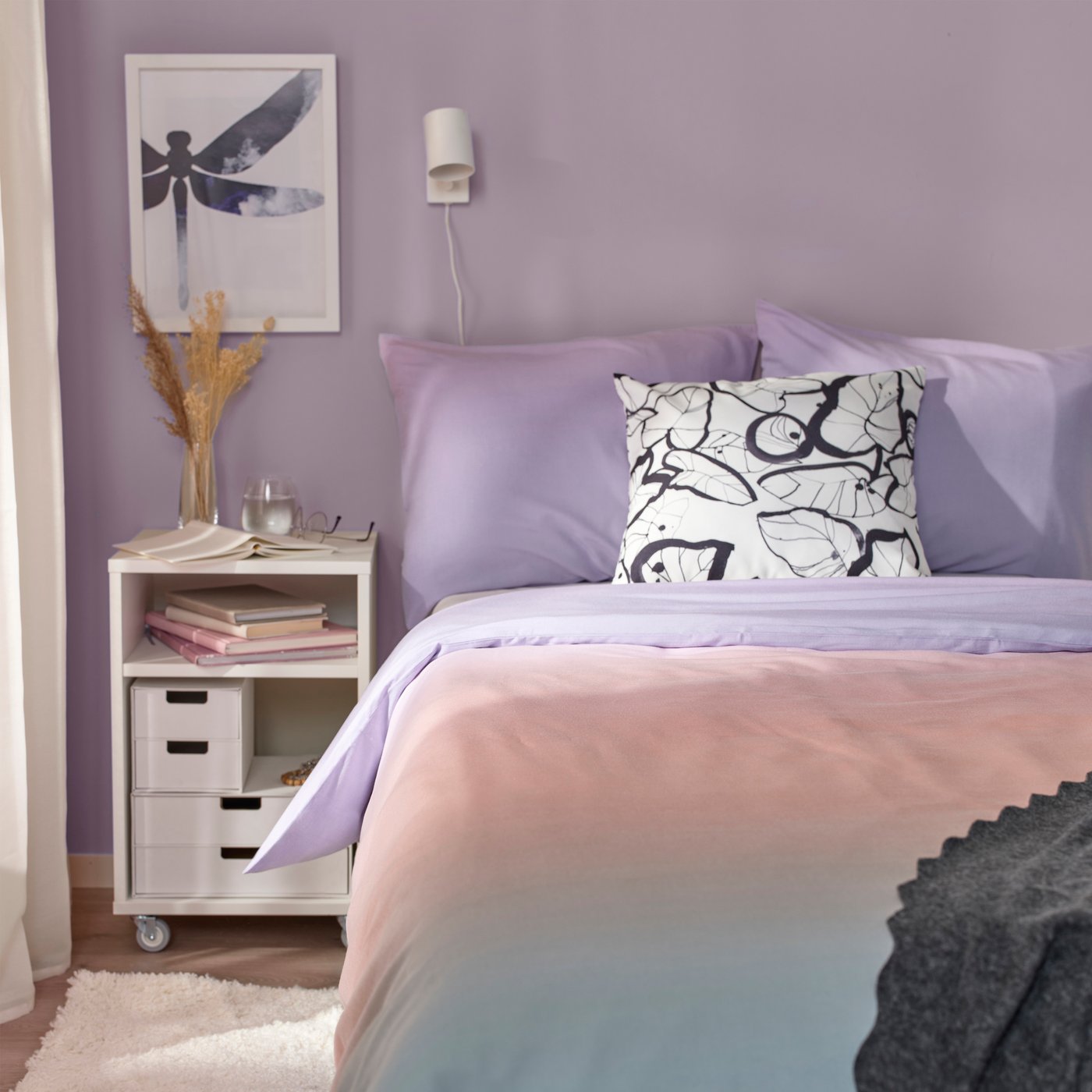 Vu d'un lit dans une chambre aux tons mauves.
