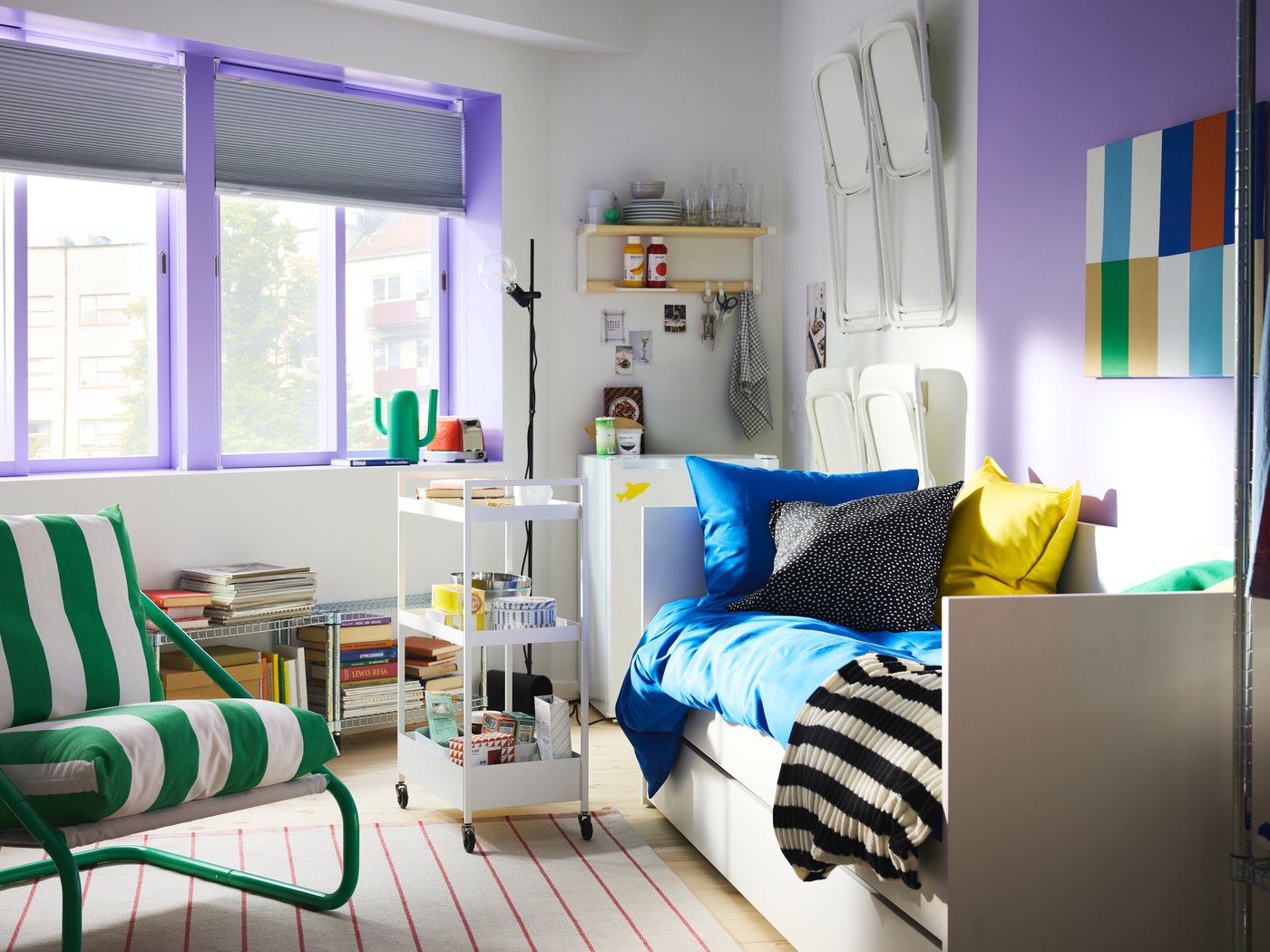 Bedroom with big windows with sash painted purple, a white daybed, a trolley on wheels and green/white ÖNNESTAD armchair.