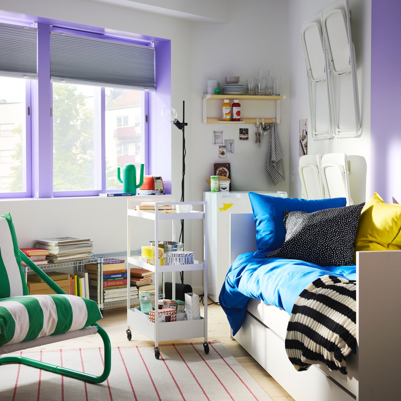 Bedroom with big windows with sash painted purple, a white daybed, a trolley on wheels and green/white ÖNNESTAD armchair.