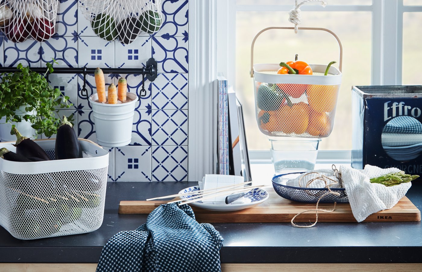 Küchenarbeitsplatte mit unterschiedlichen Lebensmitteln in RISATORP Körben oder hängend in KUNGSFORS Einkaufsnetzen.