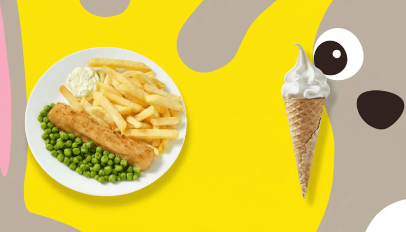 Bord met visstick, frieten, erwtjes en saus op gele achtergrond, naast een vanille-ijsje en een speelse cartoonfiguur.