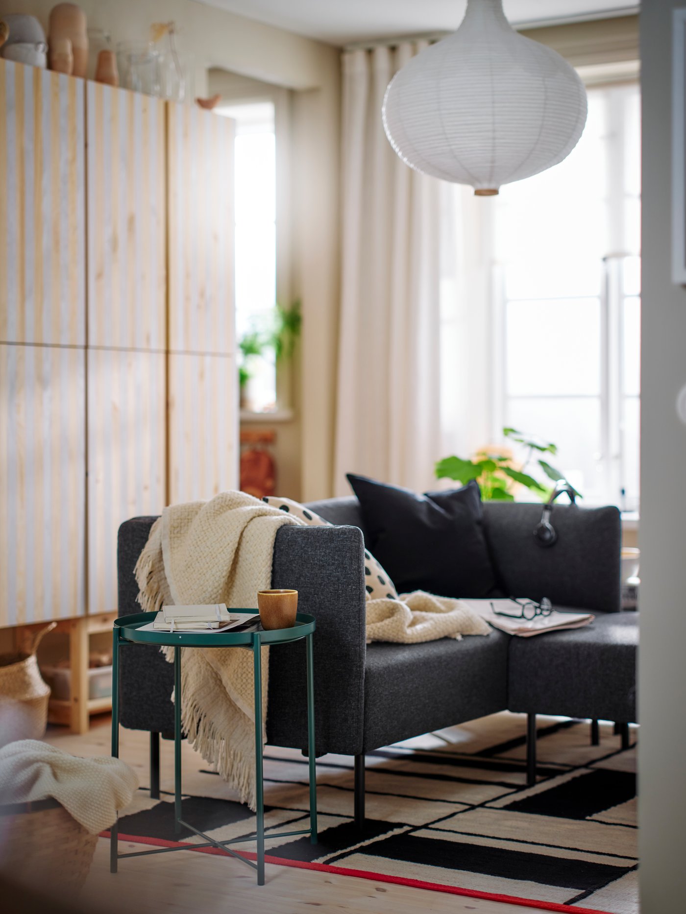 وحدات جلوس LILLEHEM وطاولة بصينية GLADOM باللون الرمادي-الأخضر الداكن فوق سجادة RASTPLATS أمام بعض وحدات تخزين IVAR.