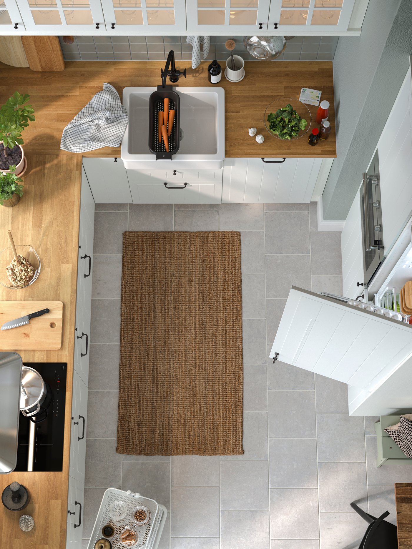 Ett kök med vita STENSUND lådfronter och vitrinluckor, ekmönstrade bänkskivor och en vit diskho.