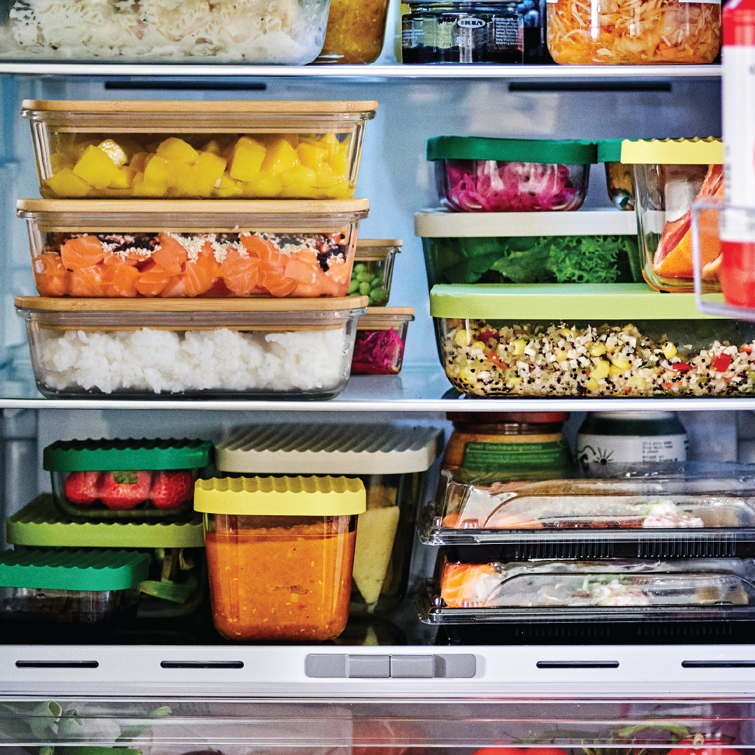 Une pile de plusieurs contenants alimentaires de différentes tailles, remplis de fruits et de légumes.