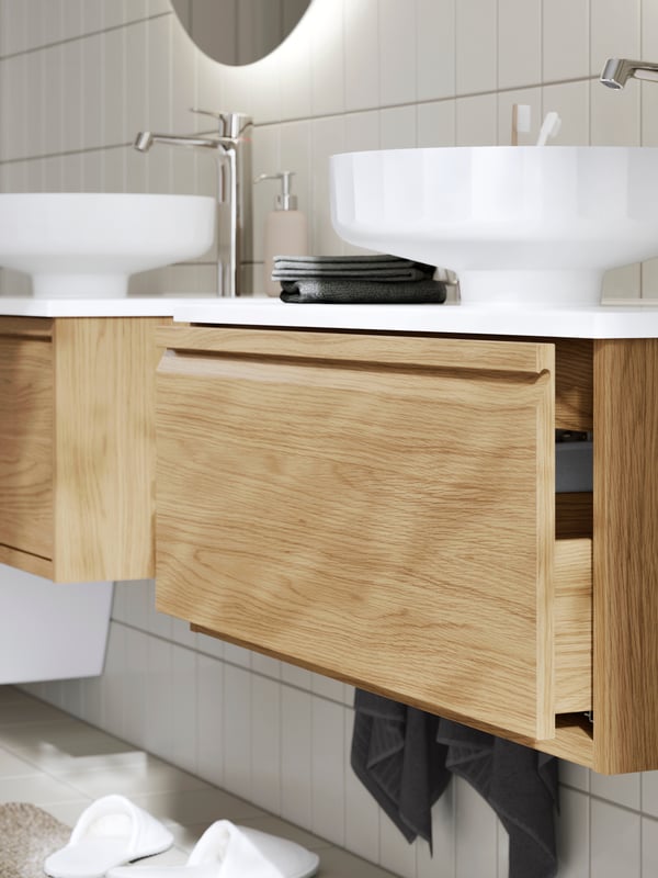 Closed ÄNGSJÖN vanity with double sinks, toothbrushes, and folded towels on the white countertop.