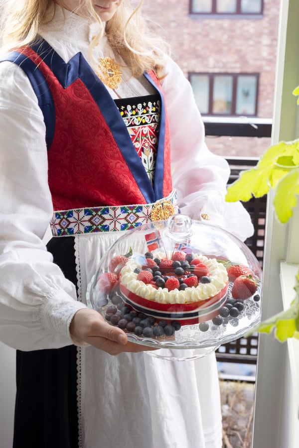 En bunadskledd jente holder kaken i et kakefat  til 17. mai.
