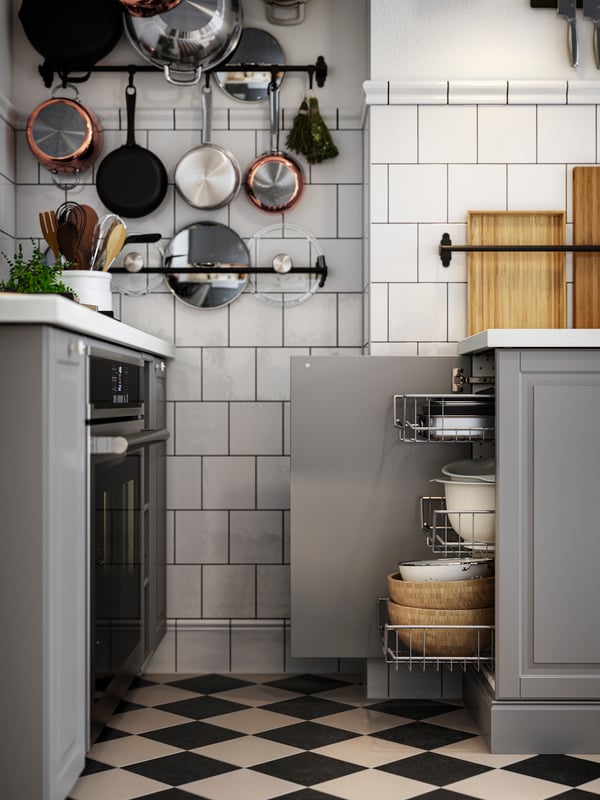 A base cabinet with the door open and mesh baskets drawn out next to a hob and oven in a kitchen with grey BODBYN fronts.