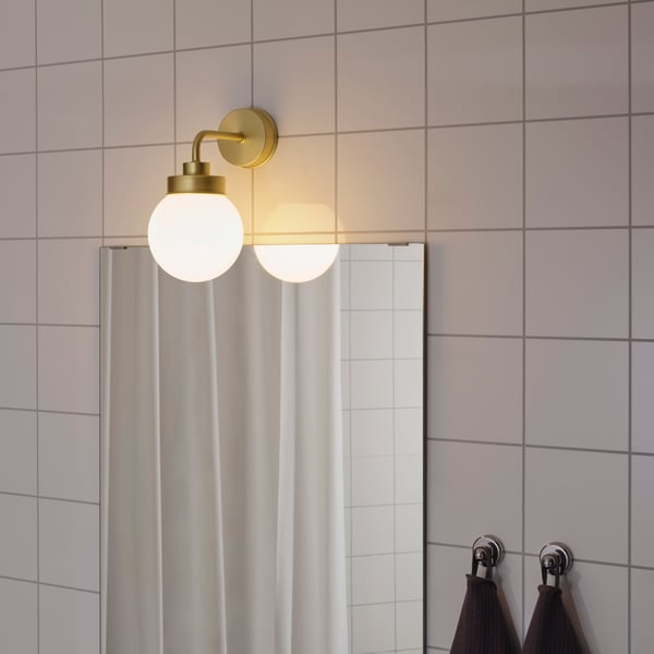 A brass-colour FRIHULT wall lamp