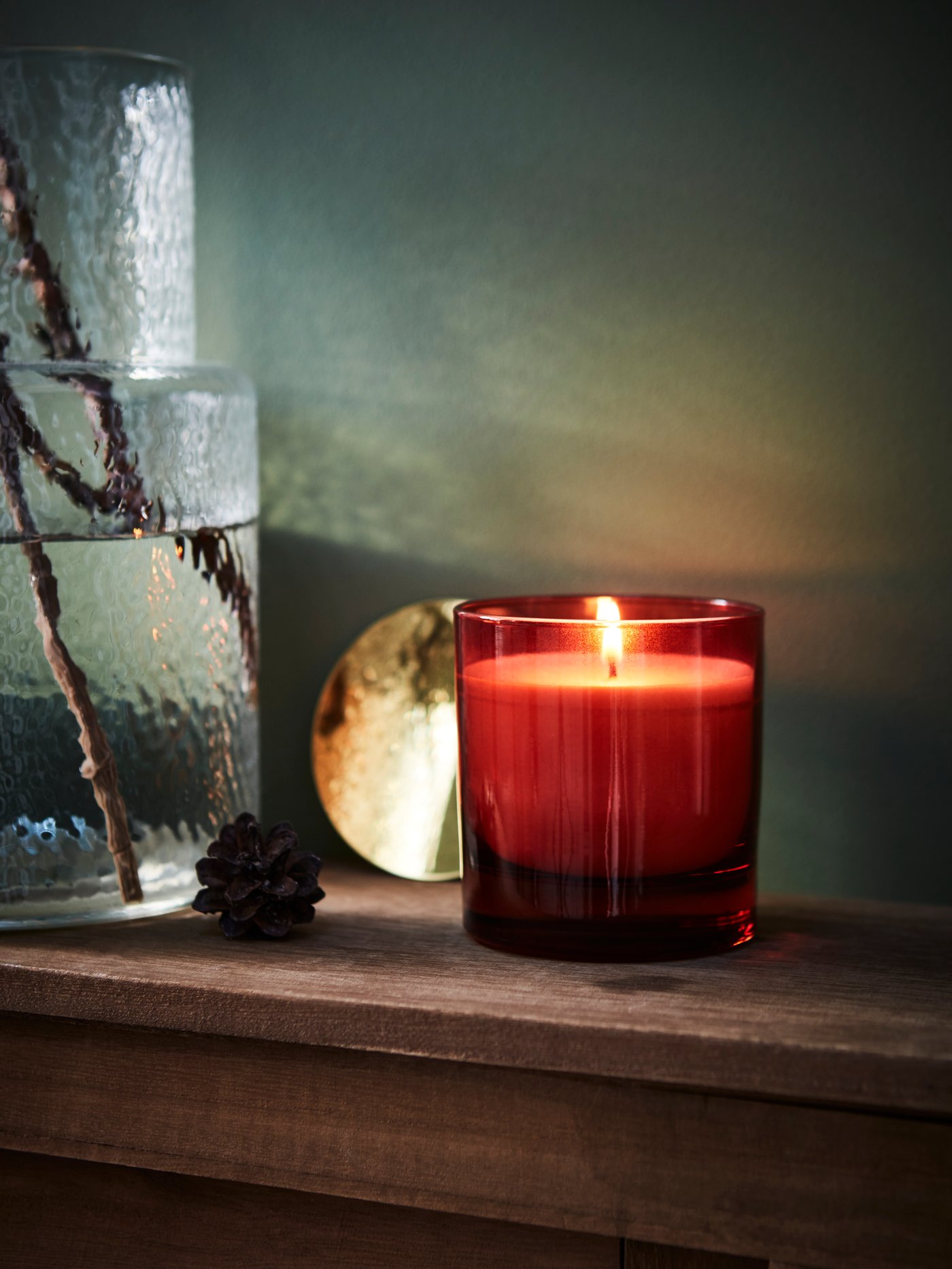 The VINTERFINT 2022 scented candle in glass with lid is lit and placed on a shelf.