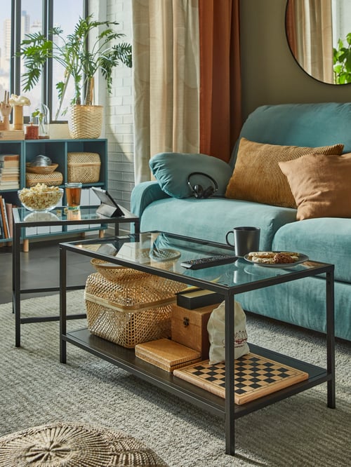 Living room with a rectangular nest of table set of 2 made of tempered glass placed on a rug high pile next to a 3 seat sofa.