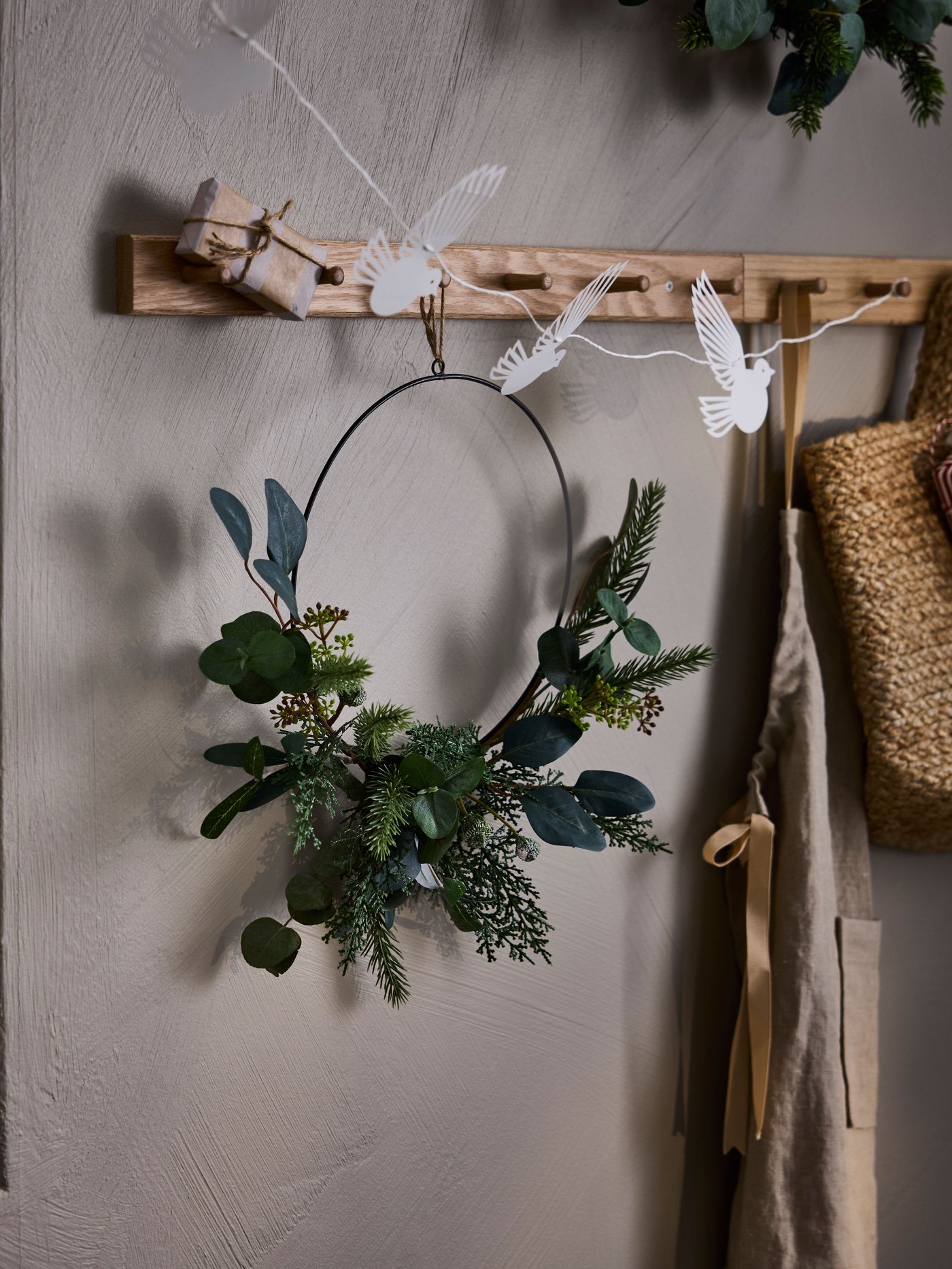Una corona de navidad VINTERFINT acolgada en un perchero de una sala.