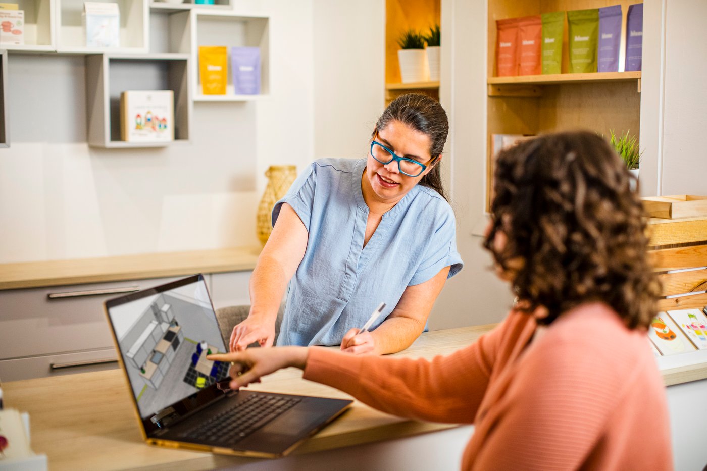 Two woman sitting around a laptop designing a kitchen with IKEA 3D planner.
