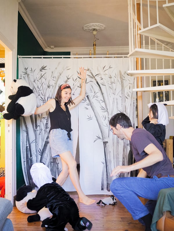 A mother, a father and two children in panda bear costumes perform a show in front of a
stage curtain made from a decorated BJÄRSEN shower curtain.