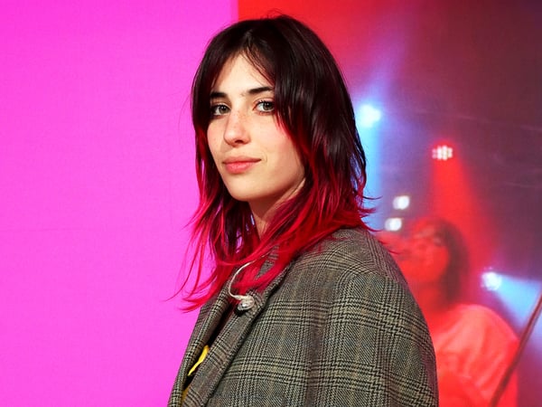 Während der Mailänder Designwoche 2024 steht Chiamamifaro am IKEA Standort auf einer Bühne. Im Hintergrund ist eine digitale Anzeige in Rosa zu sehen.