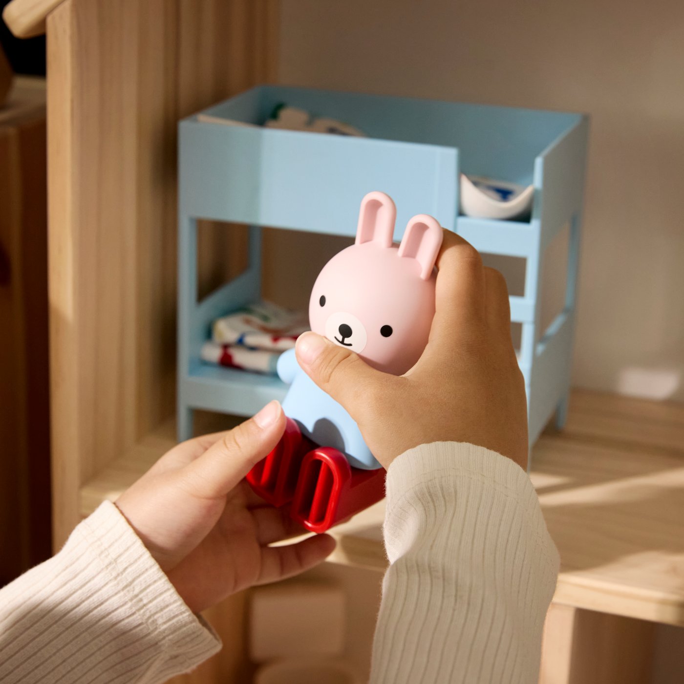 Close-up van de handen van een klein kind dat speelt met de HUSET poppenfiguren en meubels in het FLISAT poppenhuis.