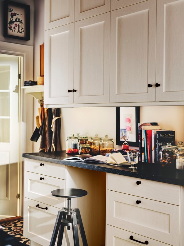 A kitchen with white ENKÖPING drawer fronts, wall cabinets with white ENKÖPING doors and a DALFRED bar stool.