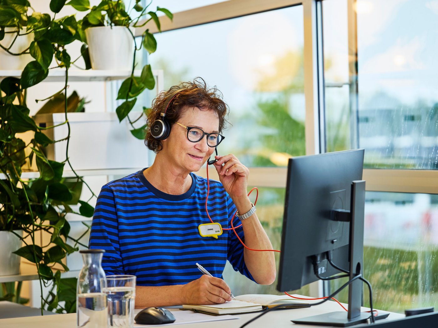 Female co-worker sitting in front of laptop with headset giving a virtual consultation