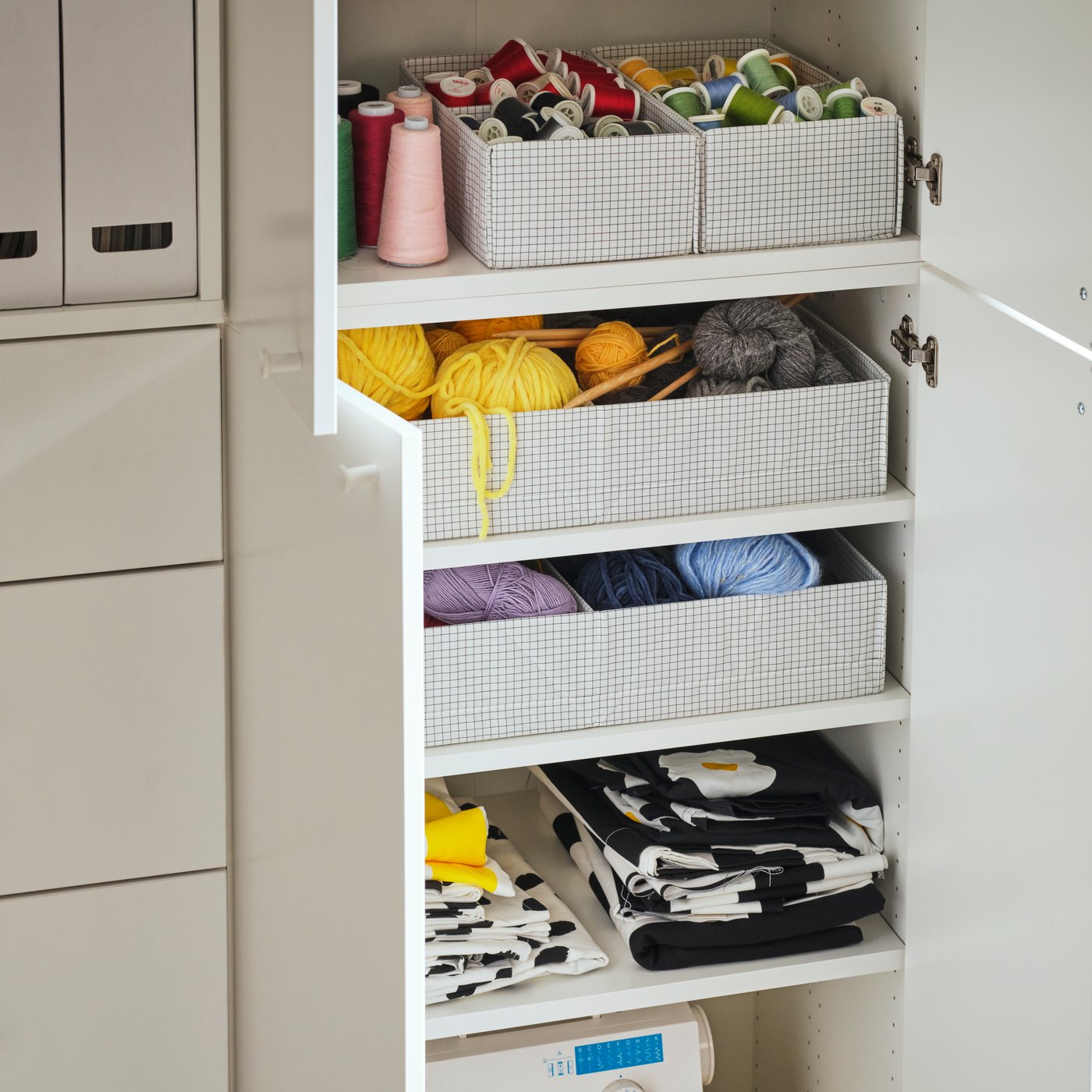 STUK boxes with compartments of different sizes containing wool and thread sit on the shelves of a LASTARE wardrobe.