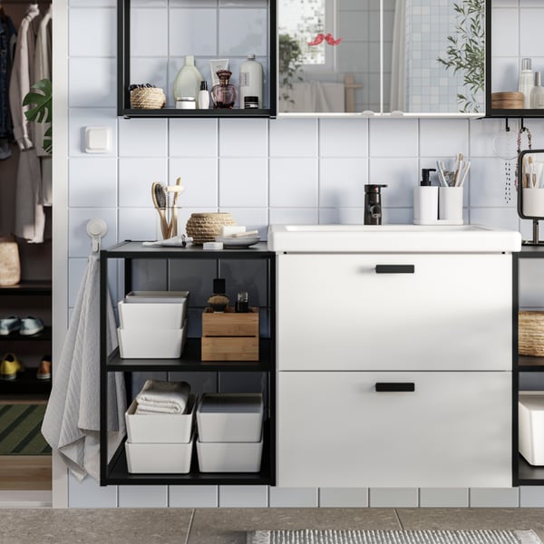A bathroom has white ENHET base cabinets and ENHET base frames with shelves in anthracite with bathroom items placed on them.