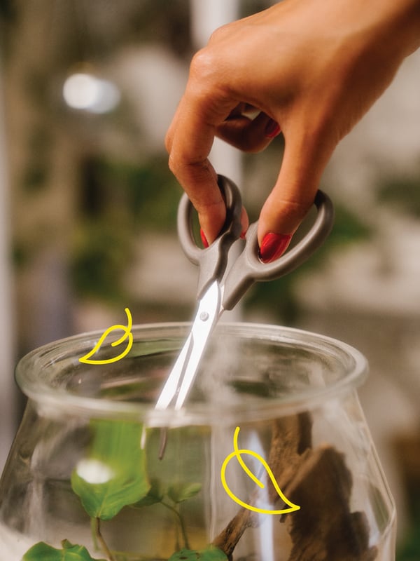 Un home talla les fulles d'un jardí en un pot amb unes tisores MÄRKBART.