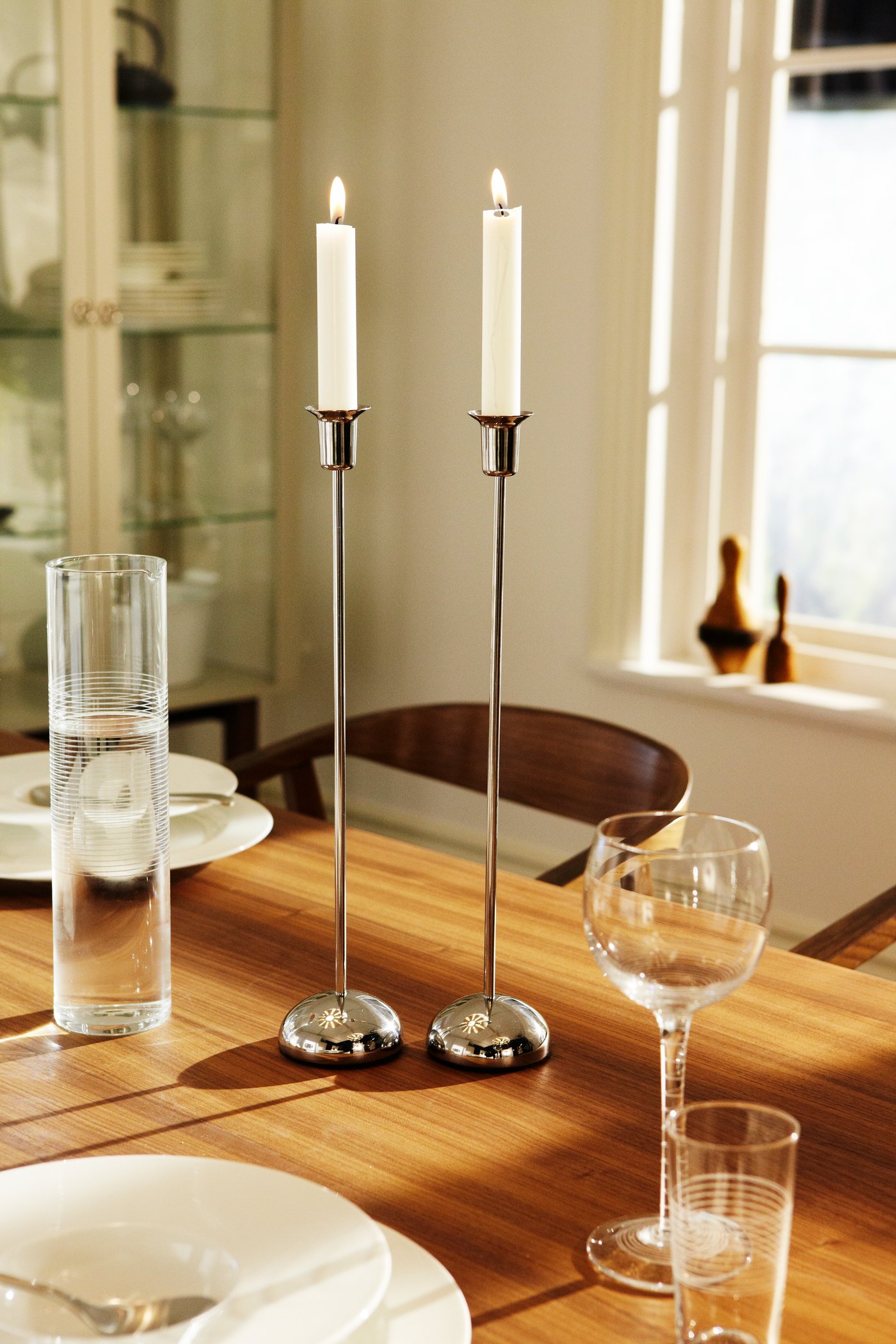 En STOCKHOLM ljusstake i rostfritt stål på ett träbord.

