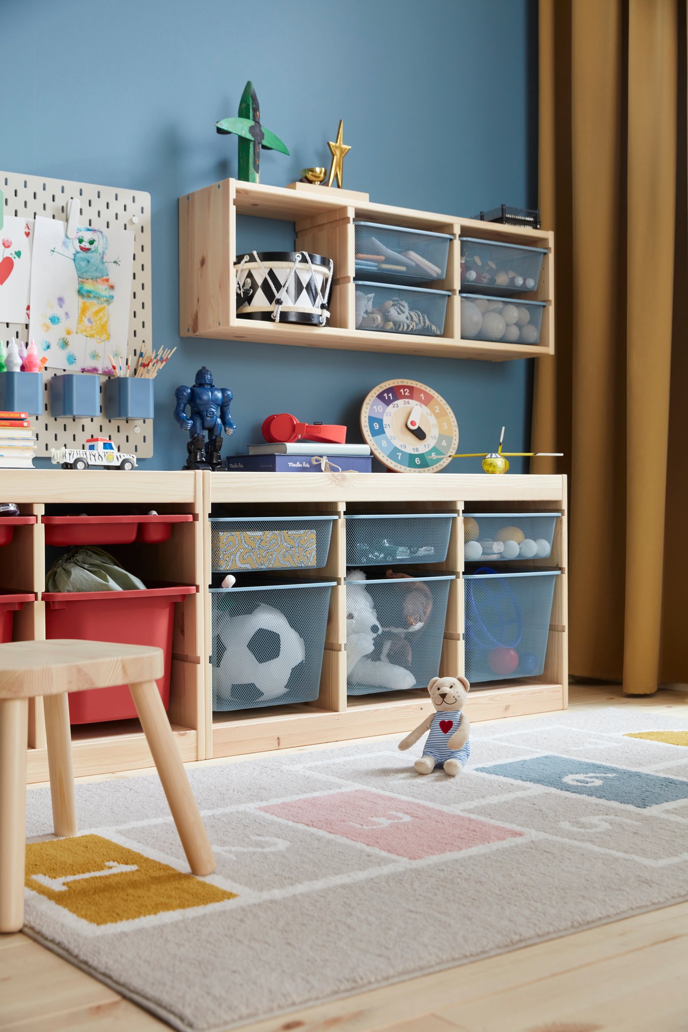 Ein TROFAST Regal aus Holz mit grau-blauen Aufbewahrungsboxen im Kinderzimmer.