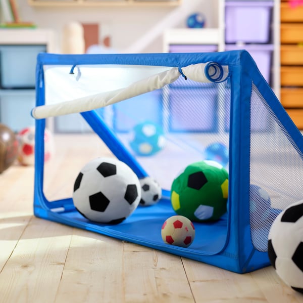 A blue SPORTSLIG ball goal and storage, full of SPARKA soft toy soccer balls.