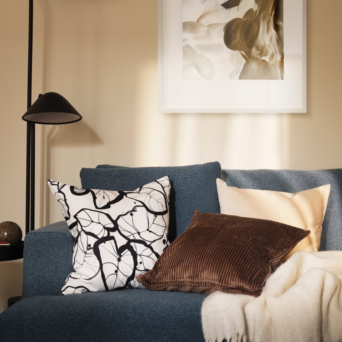 Cushions with a white/black PELARKÖRSBÄR cushion cover, a light beige SANELA cushion cover and an ÅSVEIG cushion cover.