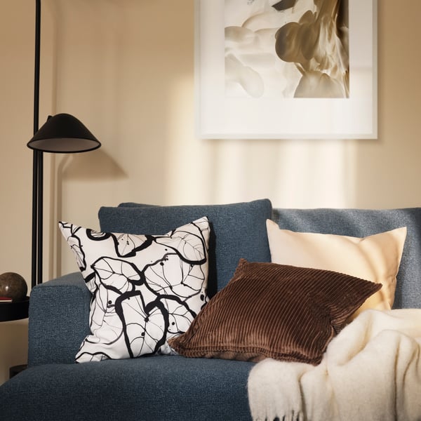 Cushions with a white/black PELARKÖRSBÄR cushion cover, a light beige SANELA cushion cover and an ÅSVEIG cushion cover.