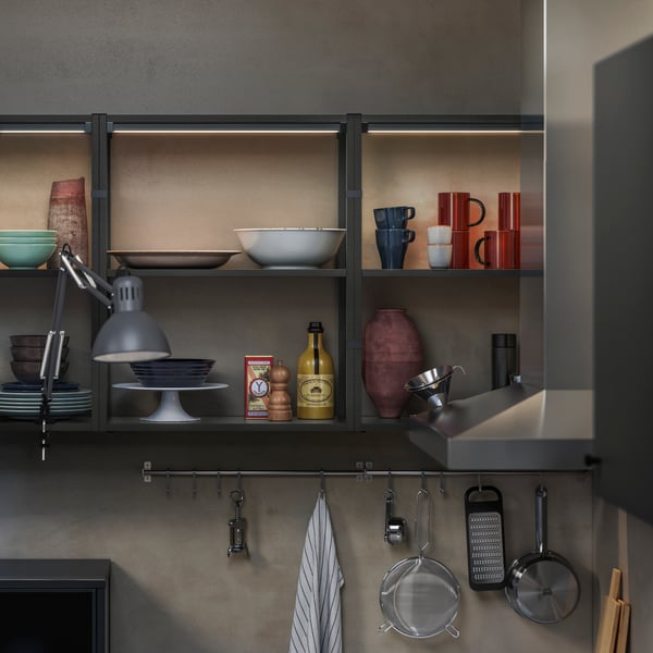 A modern kitchen shelf showcases various dishware, including a blue bowl, red mugs, and decorative bottles.