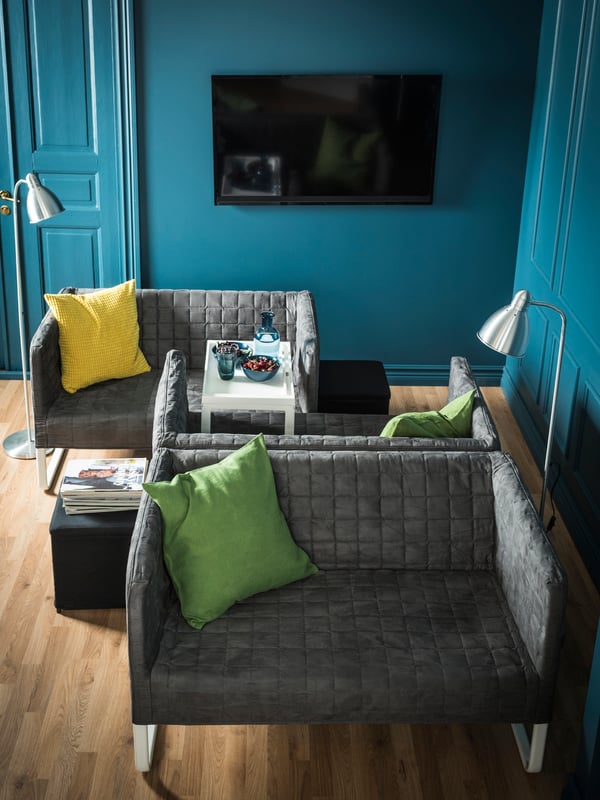Two small sofas sitting face to face, while one of them has another sofa back to back.