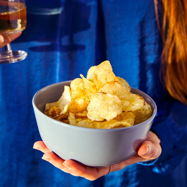 A person holding a bowl full of crisps.