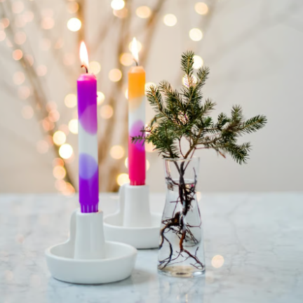 Bunte, dekorative Kerzen in einem weissen Kerzenhalter auf einem Tisch