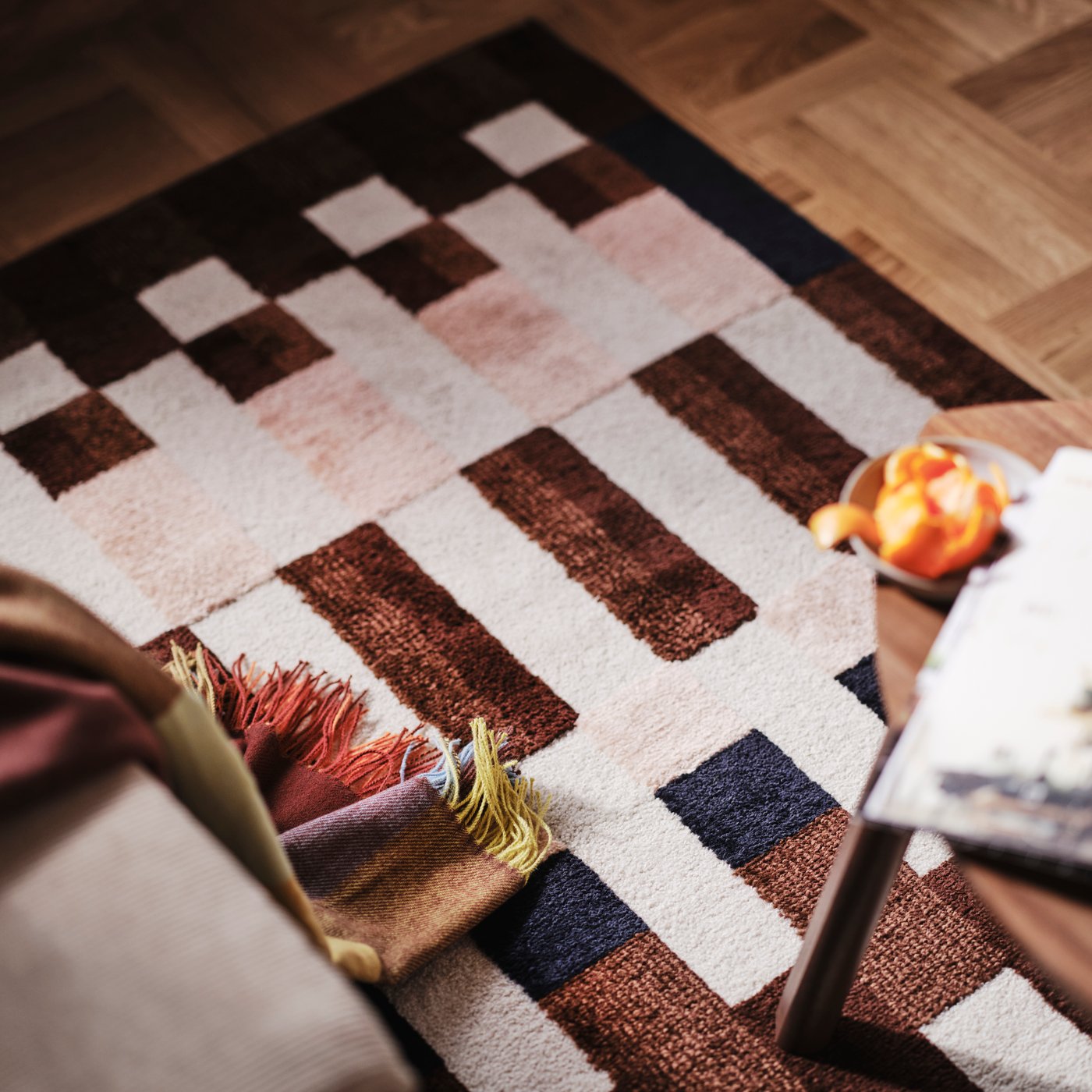 A close-up of a MARKBLÅMME low pile rug with a checkered pattern and a FLIKHAGTORN throw.