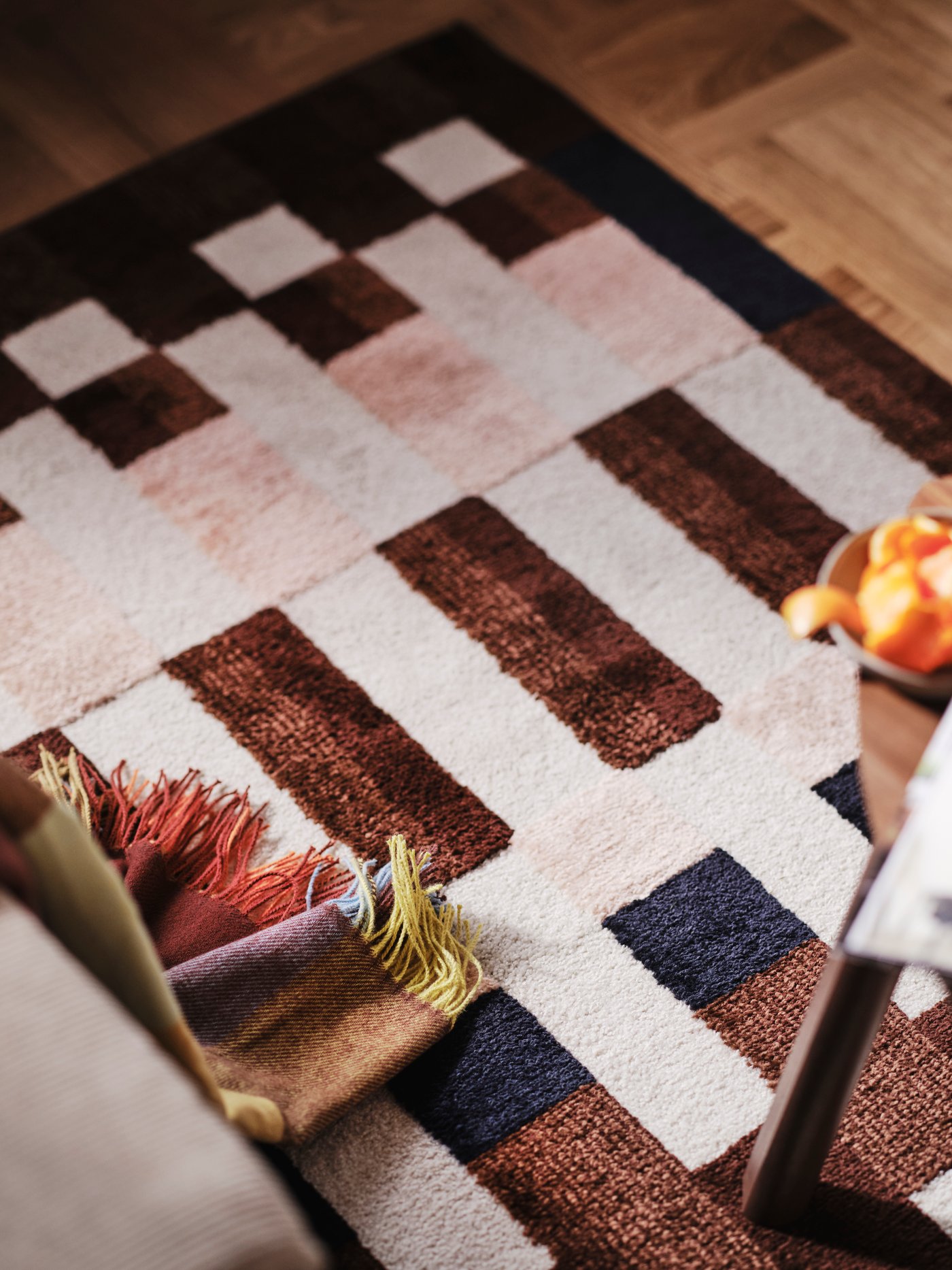 A close-up of a MARKBLÅMME low pile rug with a checkered pattern and a FLIKHAGTORN throw.