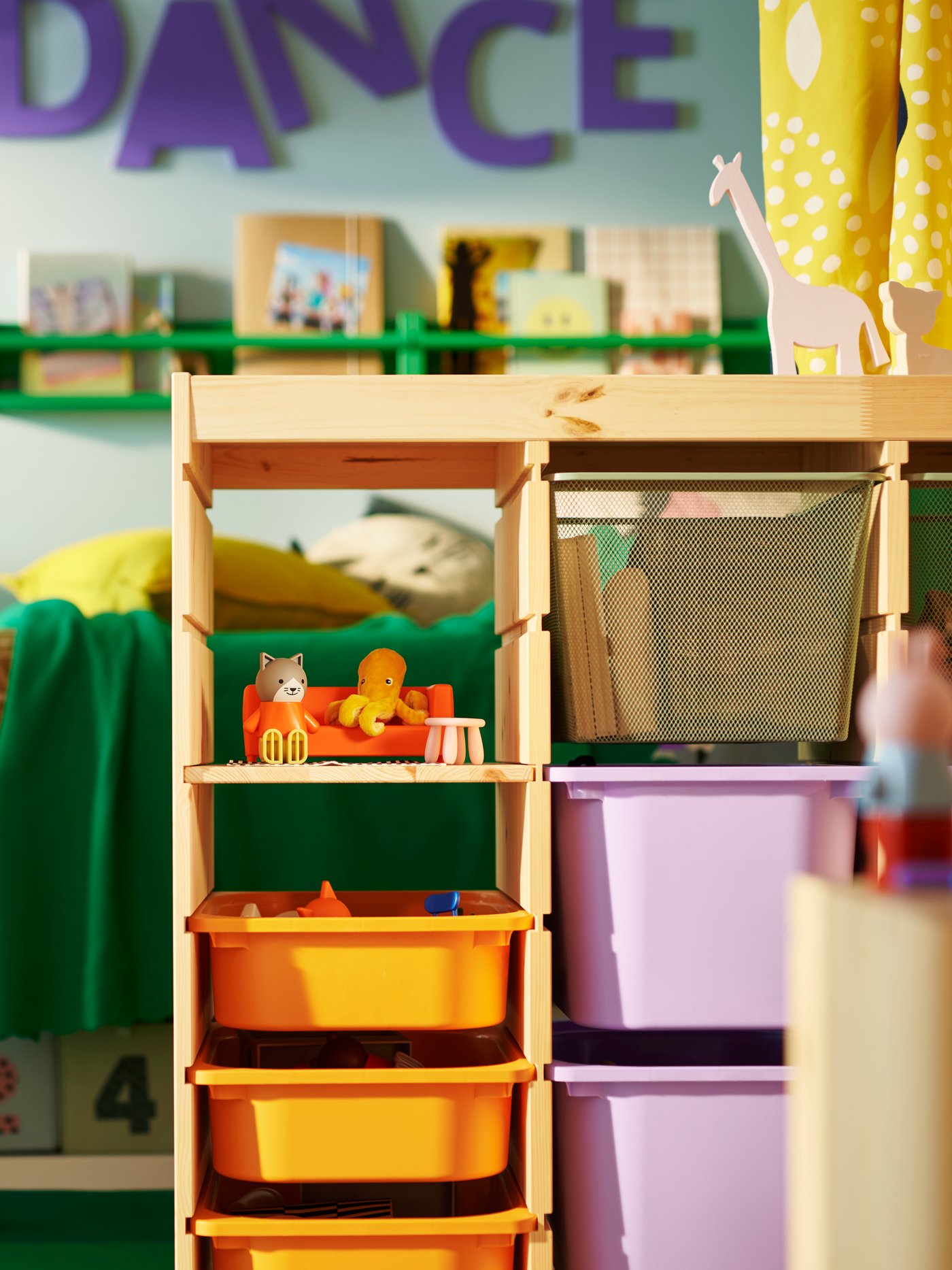 A TROFAST room divider in the middle of a children's shared bedroom holding orange, lilac and mesh boxes, with toys on top.